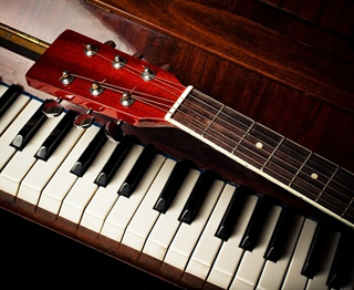 The guitar sits as a compliment to the ivory piano keys.